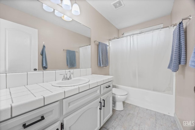 bathroom featuring toilet, wood finished floors, visible vents, vanity, and shower / bath combo