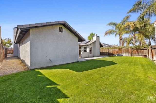 rear view of property featuring a lawn, a patio area, a fenced backyard, and stucco siding