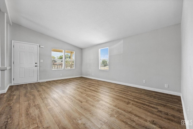 unfurnished room with hardwood / wood-style flooring and lofted ceiling