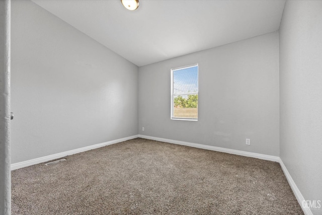 carpeted empty room featuring vaulted ceiling