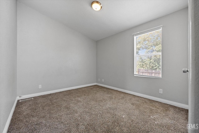 carpeted spare room featuring vaulted ceiling