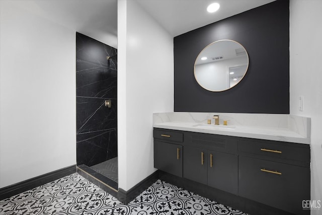 bathroom with a tile shower, vanity, and tile patterned flooring