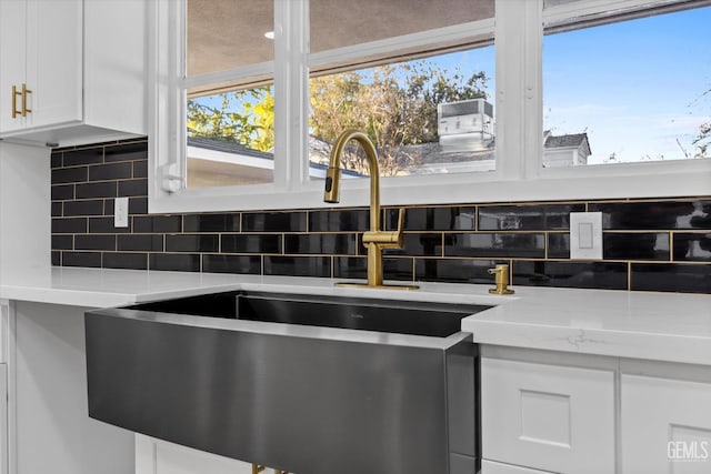 kitchen with sink, white cabinetry, tasteful backsplash, a wealth of natural light, and light stone countertops