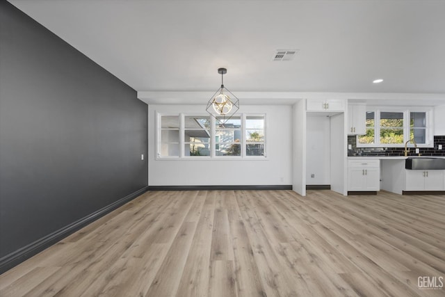 unfurnished dining area featuring plenty of natural light, sink, and light hardwood / wood-style flooring