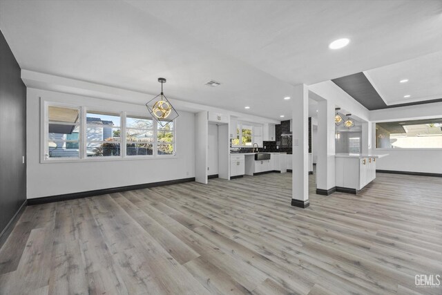 unfurnished living room featuring sink and light hardwood / wood-style floors