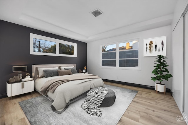 bedroom with hardwood / wood-style floors and a tray ceiling