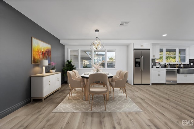 dining area with sink, a healthy amount of sunlight, and light wood-type flooring