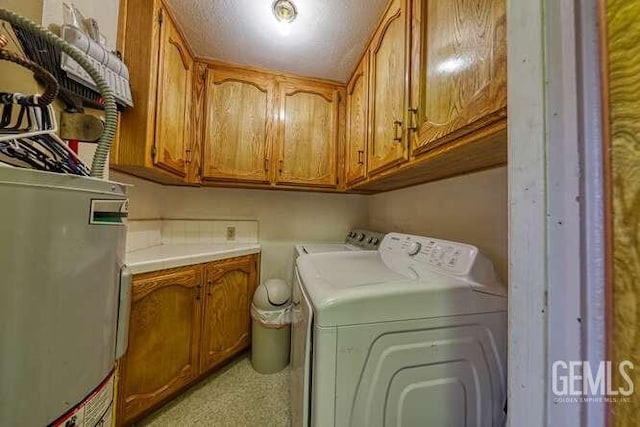 laundry area with cabinets, gas water heater, and washer and dryer