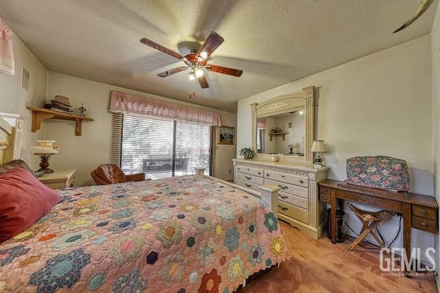 bedroom with a textured ceiling, light colored carpet, and ceiling fan