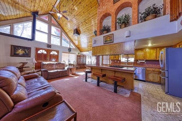 living room featuring ceiling fan, a healthy amount of sunlight, wood ceiling, and high vaulted ceiling