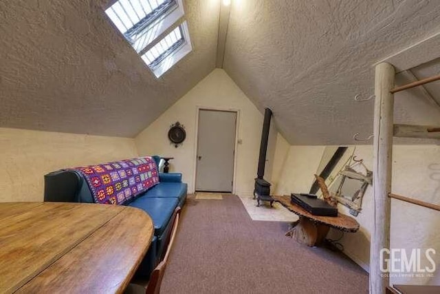 additional living space with carpet, a textured ceiling, a wood stove, and vaulted ceiling with skylight