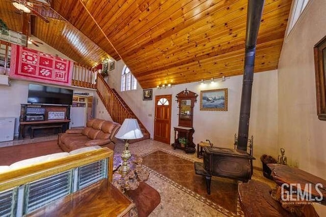 living room with a wood stove, high vaulted ceiling, and wooden ceiling