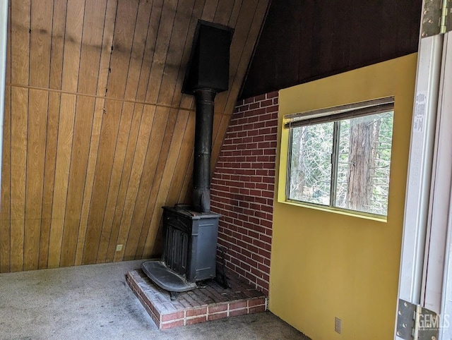 interior details featuring a wood stove, wood walls, and carpet floors