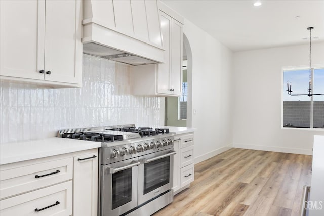 kitchen with custom exhaust hood, range with two ovens, light countertops, and tasteful backsplash