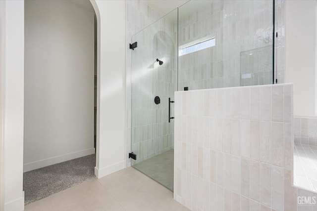 bathroom with tile patterned floors, baseboards, and tiled shower