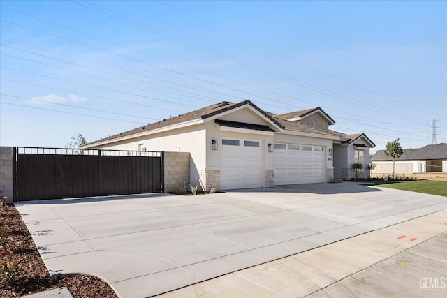 view of side of property with a gate, an attached garage, stucco siding, concrete driveway, and stone siding