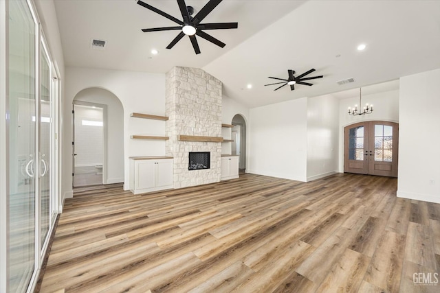 unfurnished living room featuring visible vents, ceiling fan with notable chandelier, and french doors