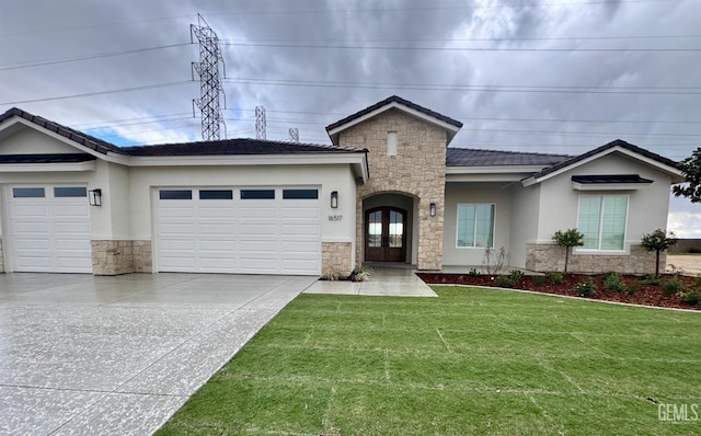 ranch-style house featuring a front lawn, french doors, a garage, stone siding, and driveway