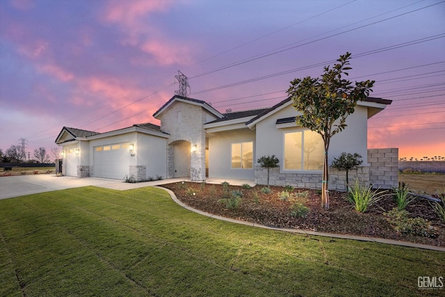 view of front of property featuring stucco siding, a lawn, driveway, stone siding, and an attached garage