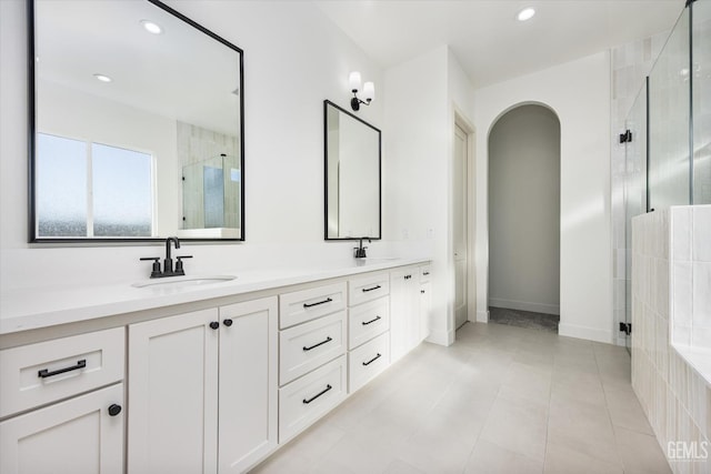 bathroom with a sink, recessed lighting, a shower stall, double vanity, and baseboards