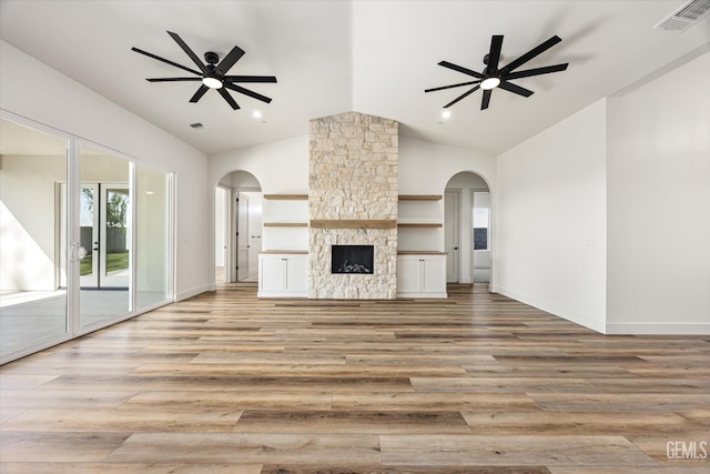 unfurnished living room featuring a ceiling fan, visible vents, arched walkways, and light wood-type flooring