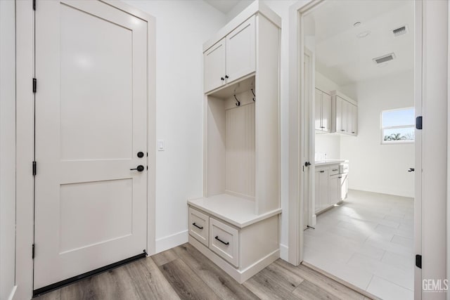 mudroom with light wood finished floors, visible vents, and baseboards