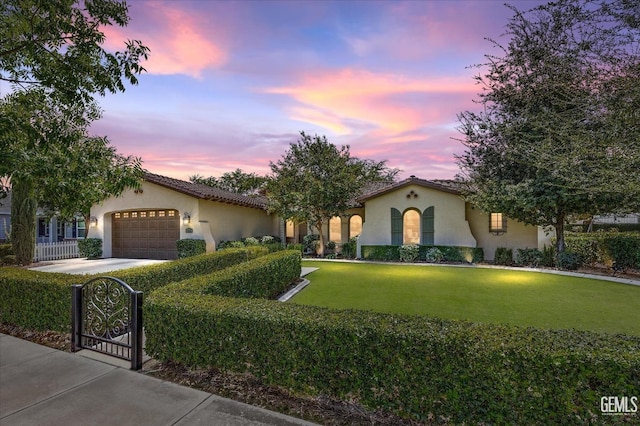 mediterranean / spanish home featuring a garage and a lawn