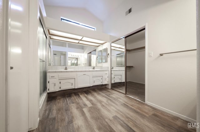 8226 Birmingham St, Bakersfield, CA 93311 - bathroom with double vanity, wood finished floors, vaulted ceiling, a walk in closet, and baseboards