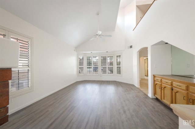 8226 Birmingham St, Bakersfield, CA 93311 - unfurnished living room featuring ceiling fan, arched walkways, wood finished floors, baseboards, and high vaulted ceiling