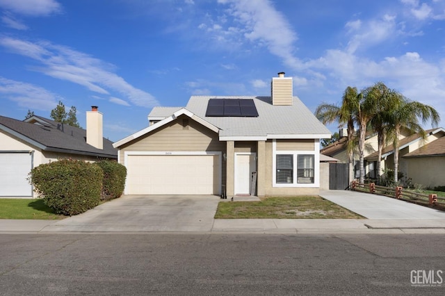 view of front facade featuring a chimney, solar panels, fence, a garage, and driveway