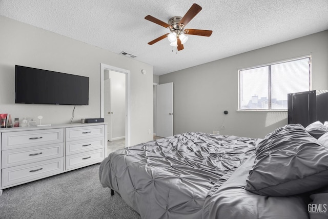 bedroom featuring light carpet, ceiling fan, visible vents, and a textured ceiling