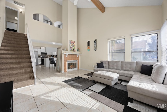 living room featuring beam ceiling, light tile patterned floors, visible vents, stairway, and a tiled fireplace