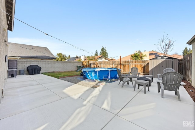 view of patio / terrace with a shed, an outdoor structure, a fenced in pool, and a fenced backyard