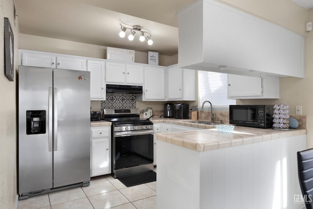 kitchen with tile counters, stainless steel appliances, under cabinet range hood, white cabinetry, and a sink