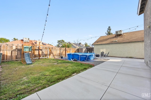 view of yard with a fenced backyard, a playground, a fenced in pool, and a patio