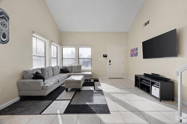 living room featuring high vaulted ceiling, baseboards, light tile patterned floors, and visible vents