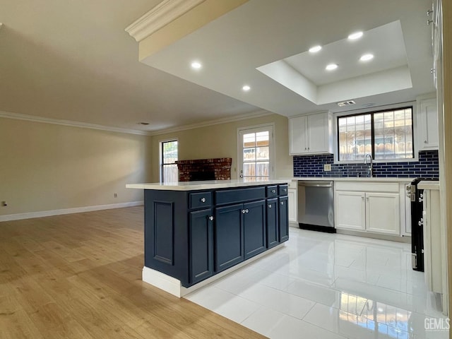 kitchen with white cabinetry, ornamental molding, appliances with stainless steel finishes, a tray ceiling, and decorative backsplash