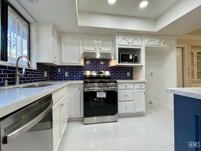 kitchen with sink, white cabinetry, stainless steel appliances, decorative backsplash, and a raised ceiling