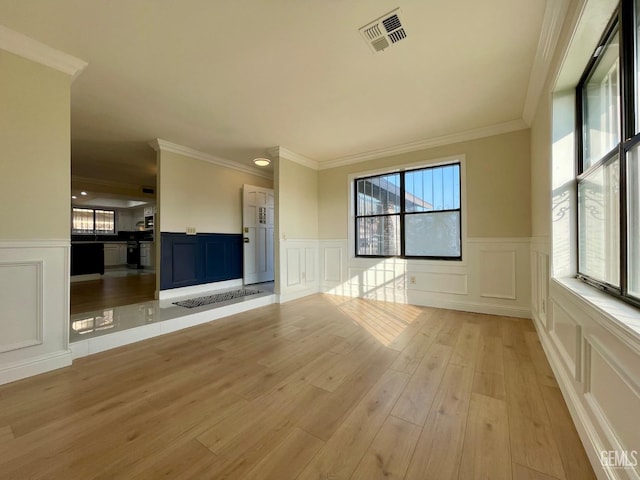 unfurnished living room featuring crown molding, plenty of natural light, and light hardwood / wood-style flooring