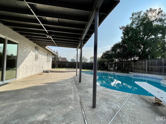 view of swimming pool with a patio area and a diving board