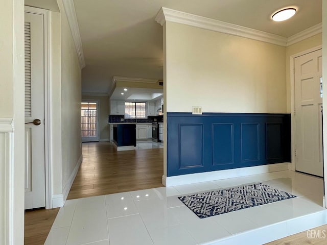 foyer with ornamental molding and light wood-type flooring