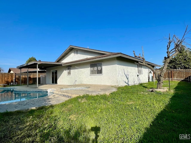 rear view of property with a fenced in pool, a yard, and a patio area