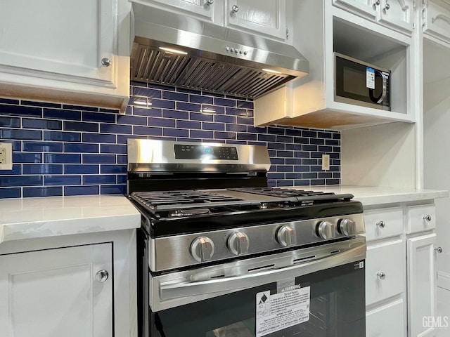 kitchen featuring extractor fan, appliances with stainless steel finishes, white cabinetry, backsplash, and light stone counters