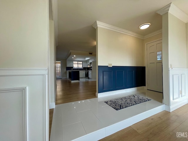 foyer entrance with ornamental molding and light hardwood / wood-style floors