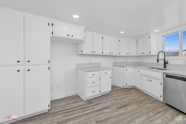 kitchen with stainless steel dishwasher, a sink, light wood finished floors, white cabinets, and recessed lighting