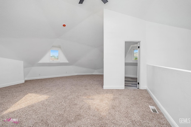 additional living space featuring carpet floors, vaulted ceiling, plenty of natural light, ceiling fan, and baseboards