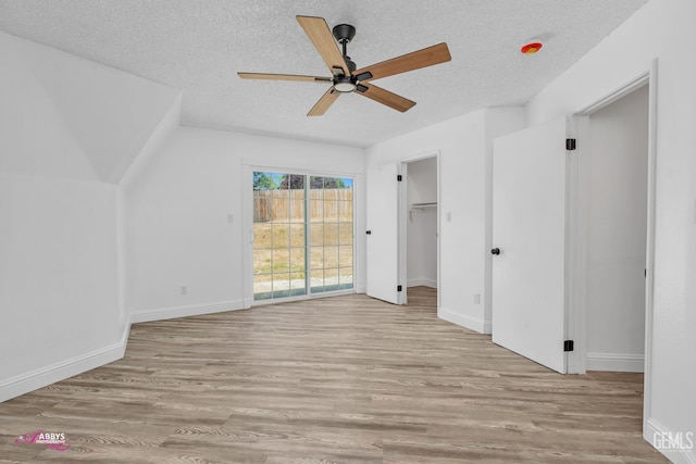 unfurnished bedroom featuring a textured ceiling, wood finished floors, access to outside, baseboards, and a ceiling fan
