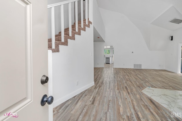 unfurnished living room featuring wood finished floors, vaulted ceiling, stairs, and baseboards
