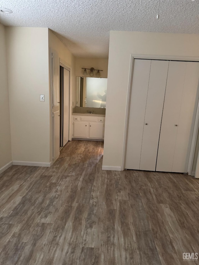 unfurnished bedroom with hardwood / wood-style flooring, ensuite bathroom, and a textured ceiling