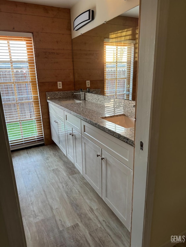 bathroom with vanity, plenty of natural light, hardwood / wood-style floors, and wood walls